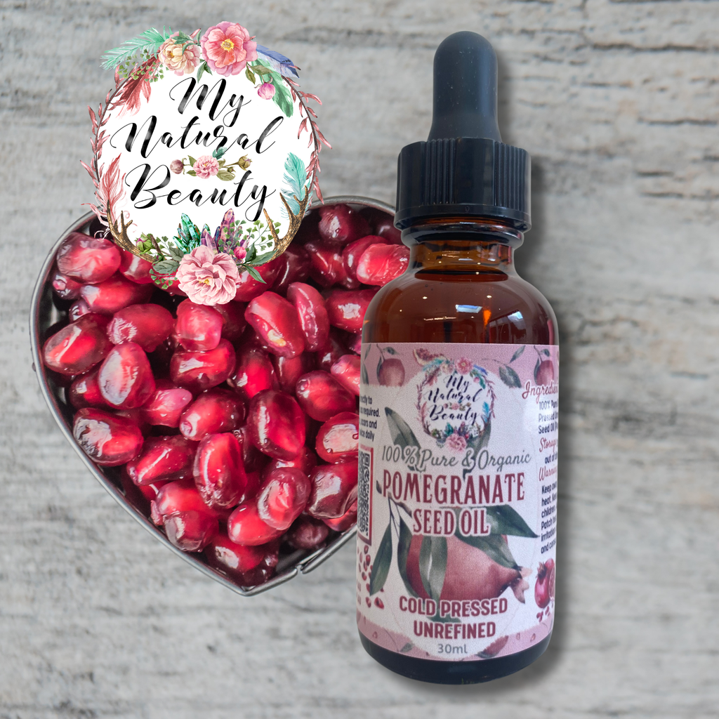 Bottle of pomegranate seed oil with a heart-shaped container of pomegranate seeds on a textured surface.